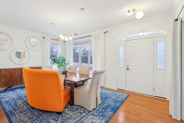 dining room with wood-type flooring, ornamental molding, and a chandelier