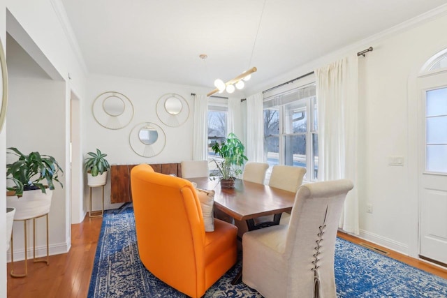 dining area featuring hardwood / wood-style flooring, ornamental molding, and a wealth of natural light