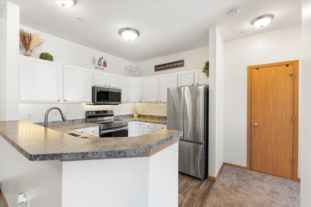 kitchen with a kitchen bar, sink, white cabinetry, appliances with stainless steel finishes, and kitchen peninsula