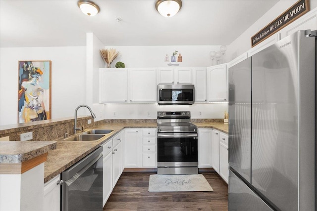 kitchen featuring sink, stainless steel appliances, white cabinets, dark hardwood / wood-style flooring, and kitchen peninsula