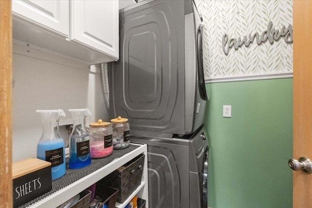 laundry area with stacked washer / dryer and cabinets