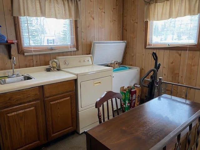 clothes washing area featuring wooden walls, washer / dryer, and sink