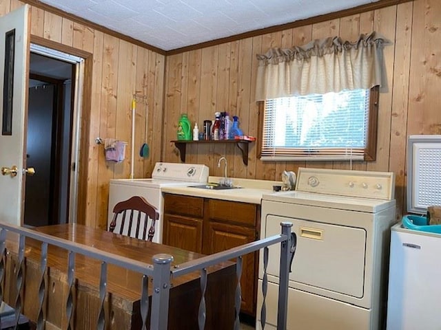 laundry room with sink, washing machine and dryer, and wood walls