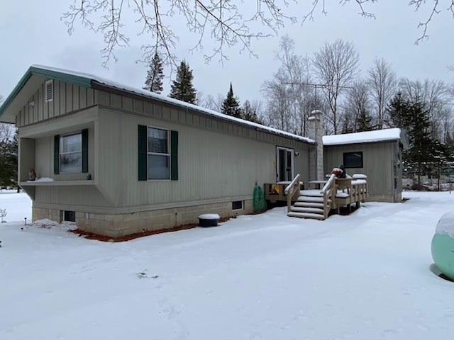 snow covered rear of property featuring a deck