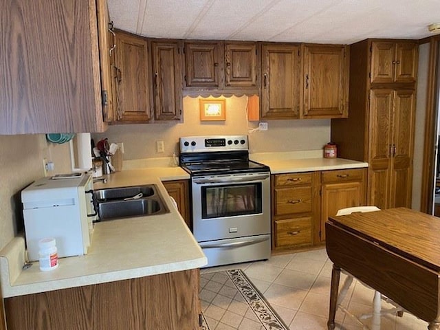 kitchen featuring stainless steel electric range oven, sink, and light tile patterned floors