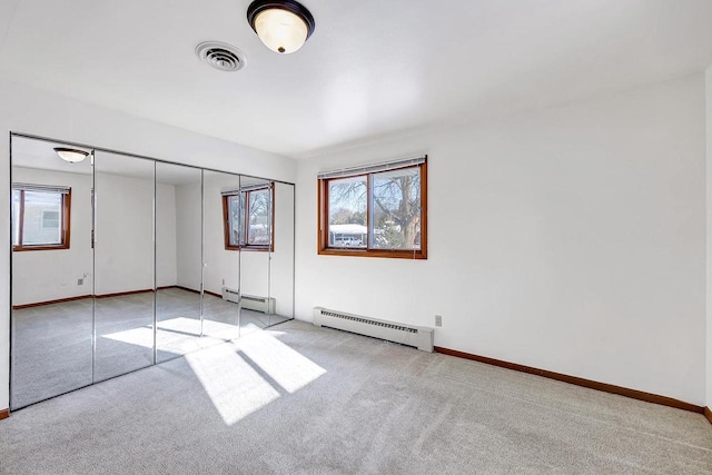 unfurnished bedroom with light carpet, a closet, and baseboard heating