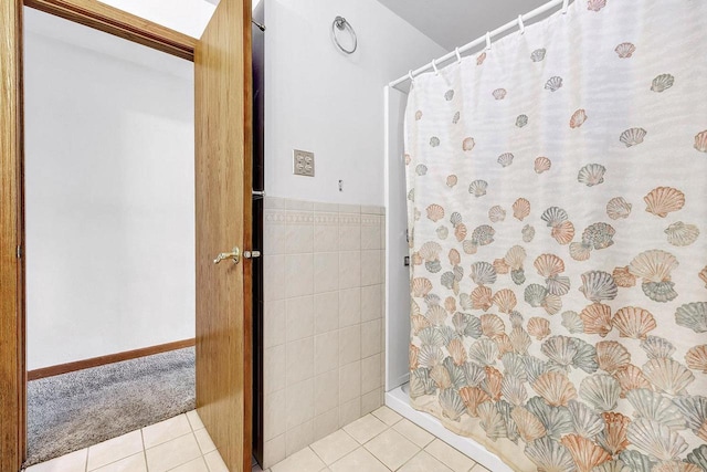 bathroom with curtained shower, tile patterned floors, and tile walls