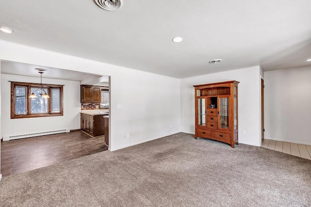 unfurnished living room featuring baseboard heating, a chandelier, and dark carpet