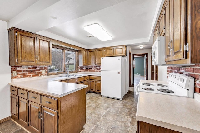 kitchen featuring tasteful backsplash, sink, white appliances, and kitchen peninsula