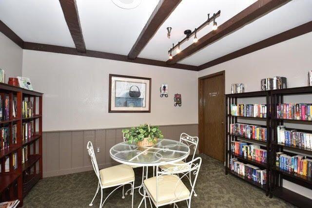 dining area with beamed ceiling and dark carpet