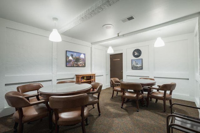 carpeted dining space featuring beam ceiling