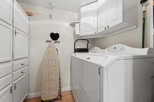 laundry area with cabinets, separate washer and dryer, and light hardwood / wood-style flooring