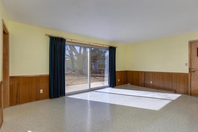 empty room featuring a wainscoted wall and wood walls