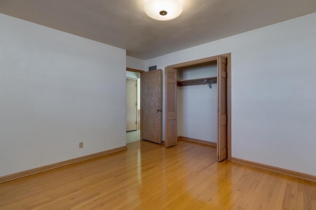 unfurnished bedroom featuring light wood finished floors, baseboards, and a closet