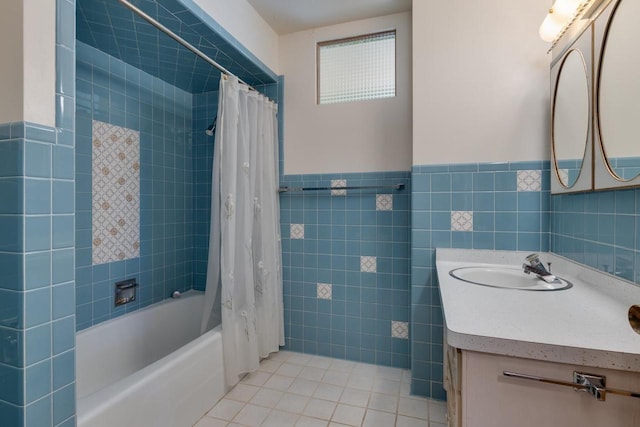 bathroom with wainscoting, tile patterned flooring, shower / bath combo with shower curtain, vanity, and tile walls