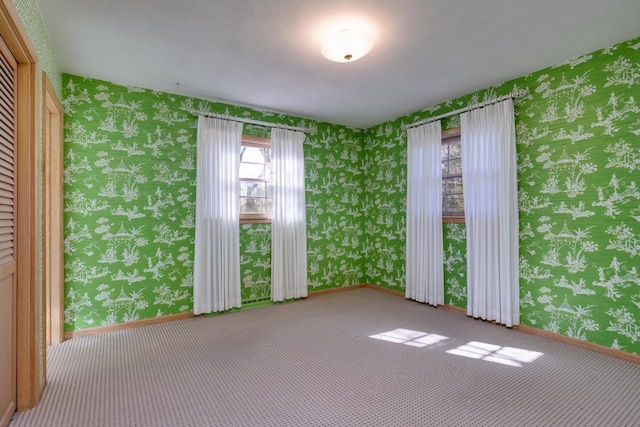 carpeted empty room with baseboards and wallpapered walls