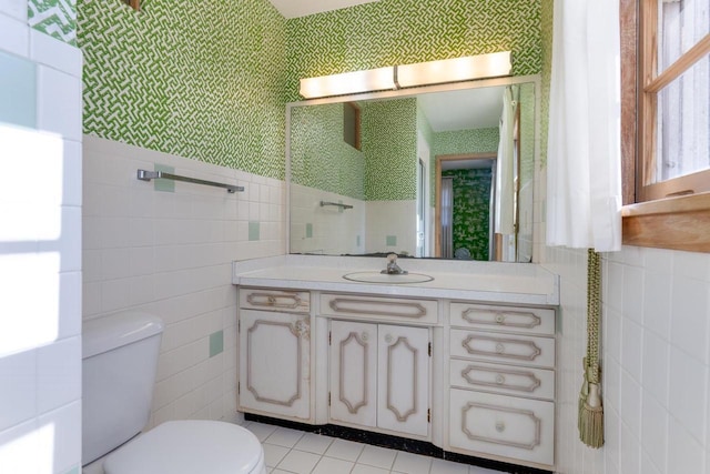 bathroom featuring toilet, vanity, tile walls, and tile patterned floors