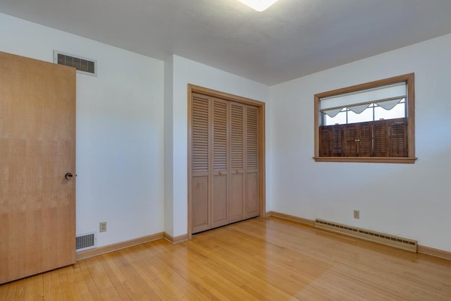 unfurnished bedroom featuring light wood finished floors, a baseboard radiator, visible vents, and baseboards