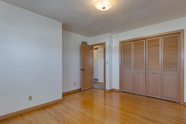 unfurnished bedroom with light wood-type flooring, a closet, visible vents, and baseboards