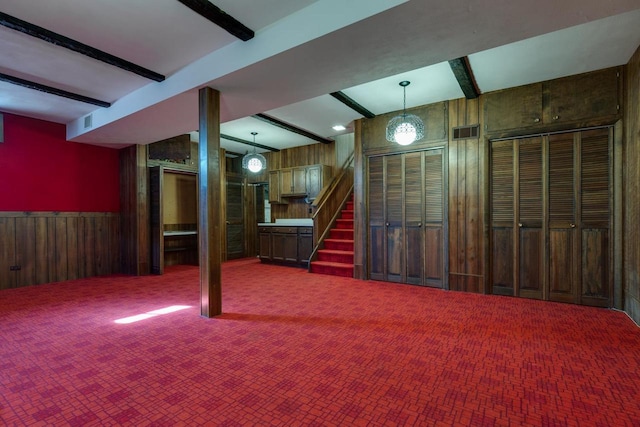 below grade area with carpet floors, visible vents, stairway, wainscoting, and wooden walls