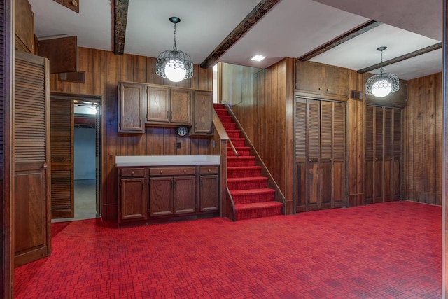 kitchen with wooden walls, pendant lighting, and beamed ceiling