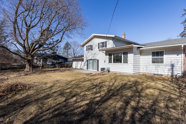 rear view of property with a chimney and a yard