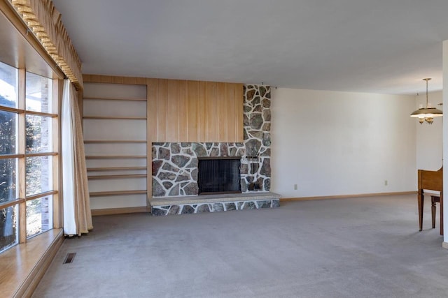 unfurnished living room featuring carpet floors, visible vents, a stone fireplace, and baseboards