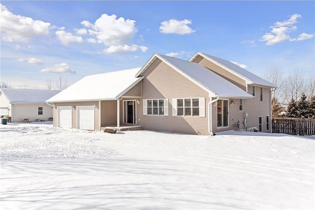 snow covered back of property with a garage