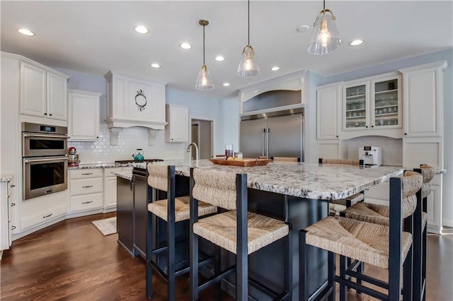 kitchen featuring white cabinetry, a spacious island, appliances with stainless steel finishes, and decorative light fixtures