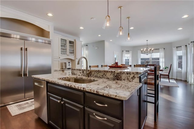 kitchen featuring sink, appliances with stainless steel finishes, a center island with sink, white cabinets, and a kitchen bar