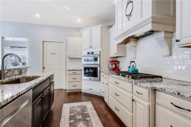 kitchen with white cabinetry, appliances with stainless steel finishes, light stone countertops, and sink