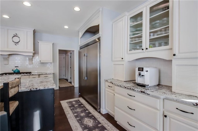 kitchen with appliances with stainless steel finishes, dark hardwood / wood-style floors, light stone countertops, white cabinets, and decorative backsplash