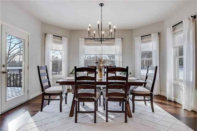 dining area with dark wood-type flooring and a notable chandelier