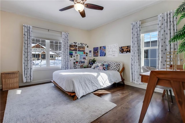 bedroom featuring ceiling fan, dark hardwood / wood-style floors, and multiple windows