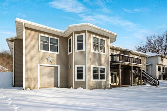 snow covered rear of property featuring a garage and a deck