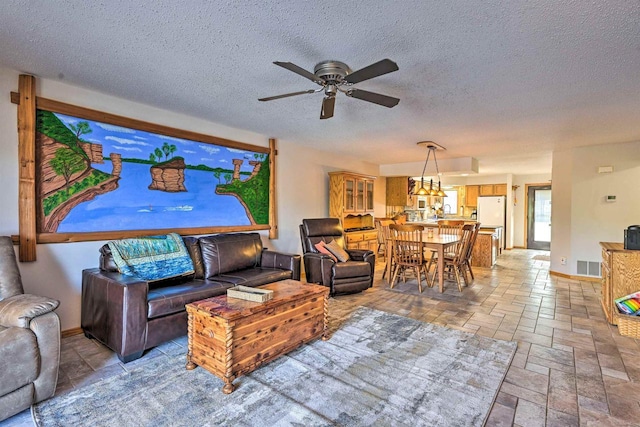 living room with a textured ceiling and ceiling fan