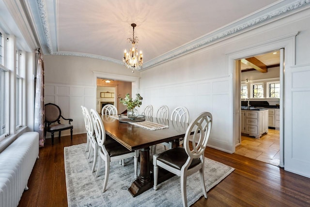 dining area with hardwood / wood-style flooring, radiator, sink, and a chandelier