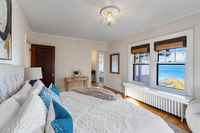 bedroom featuring an inviting chandelier, ornamental molding, radiator heating unit, and light hardwood / wood-style flooring