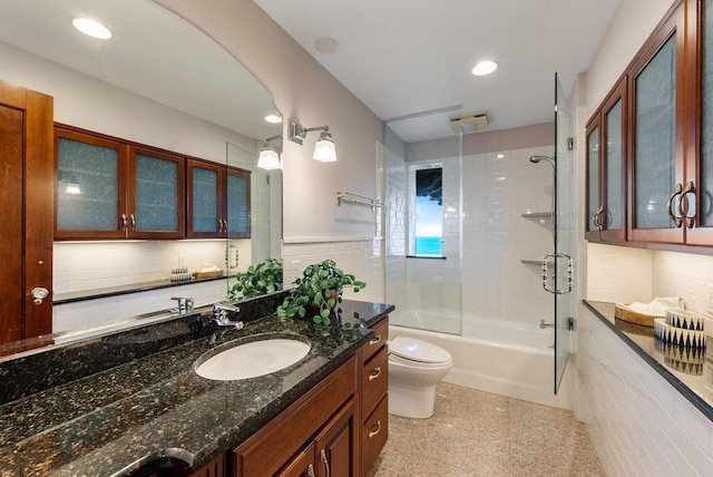 full bathroom with tasteful backsplash, tile walls, enclosed tub / shower combo, vanity, and toilet