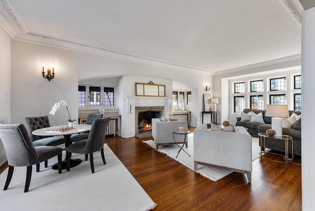 living room with dark hardwood / wood-style flooring, plenty of natural light, ornamental molding, and a premium fireplace