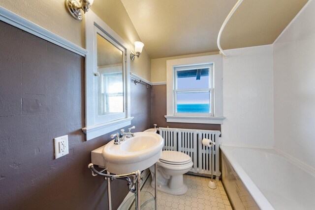 bathroom with a healthy amount of sunlight, radiator heating unit, toilet, and tile patterned floors