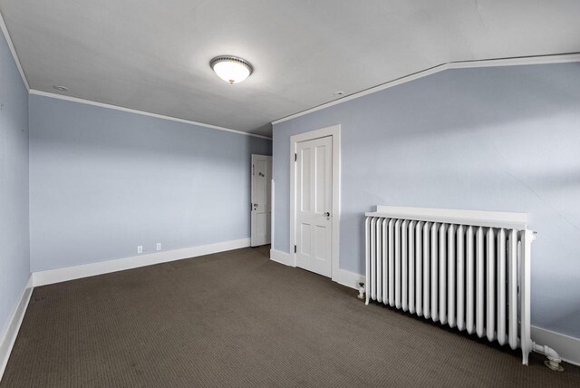 spare room with crown molding, radiator heating unit, and dark colored carpet