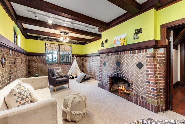 carpeted living room with rail lighting, brick wall, a fireplace, and beam ceiling