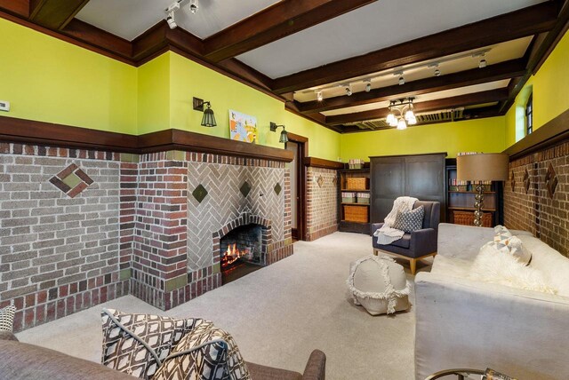 living room with beamed ceiling, brick wall, a brick fireplace, and carpet flooring