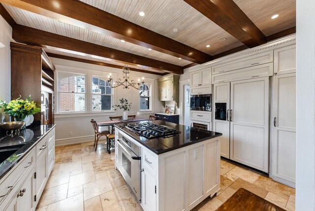 kitchen featuring pendant lighting, white cabinets, a center island, built in appliances, and beam ceiling