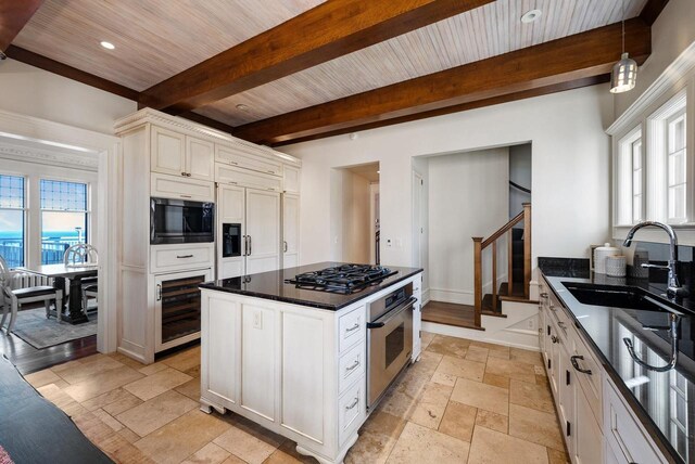 kitchen featuring appliances with stainless steel finishes, beamed ceiling, sink, a center island, and wood ceiling