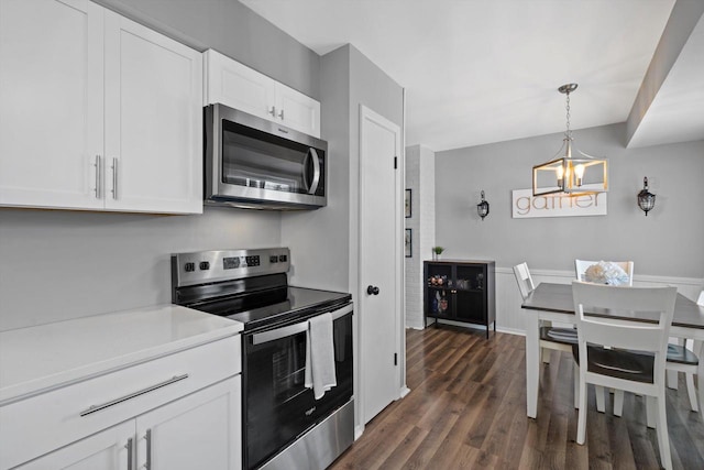 kitchen with appliances with stainless steel finishes, hanging light fixtures, a notable chandelier, white cabinets, and dark hardwood / wood-style flooring