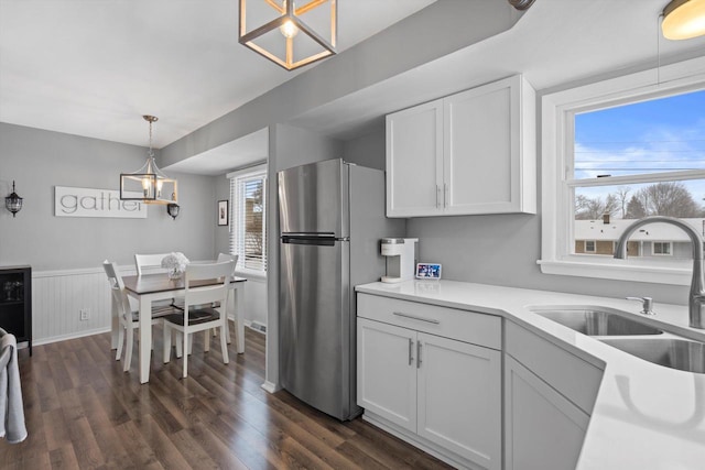 kitchen with pendant lighting, white cabinetry, sink, stainless steel fridge, and dark hardwood / wood-style flooring