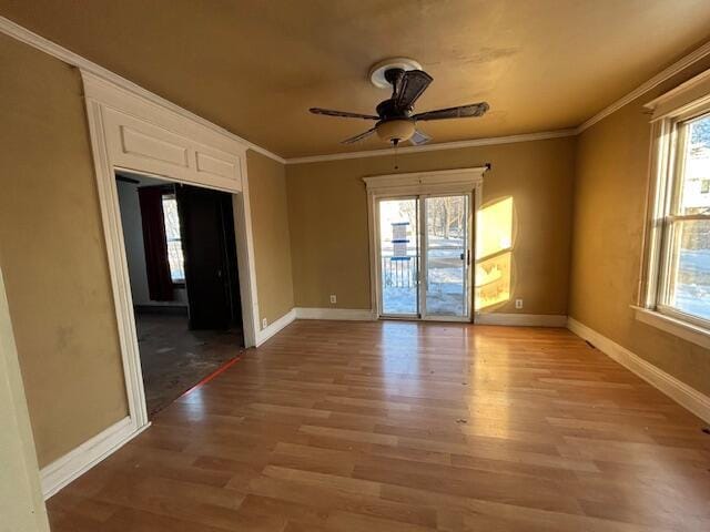 empty room with crown molding, wood-type flooring, and ceiling fan