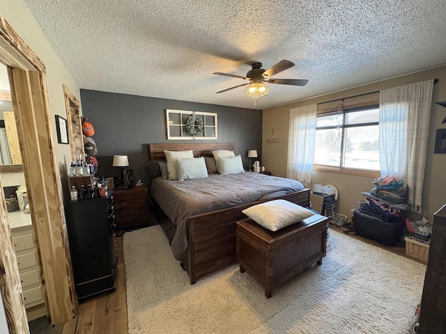 bedroom with light wood-type flooring, ceiling fan, and a textured ceiling